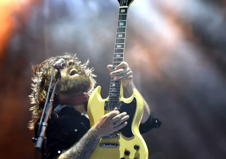 Guitarrista levantando una guitarra amarilla bajo los focos