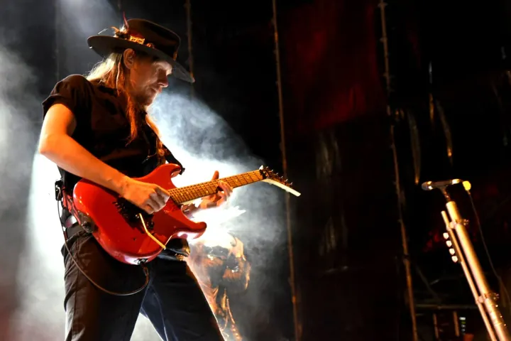 Guitarrista con sombrero tocando una guitarra roja